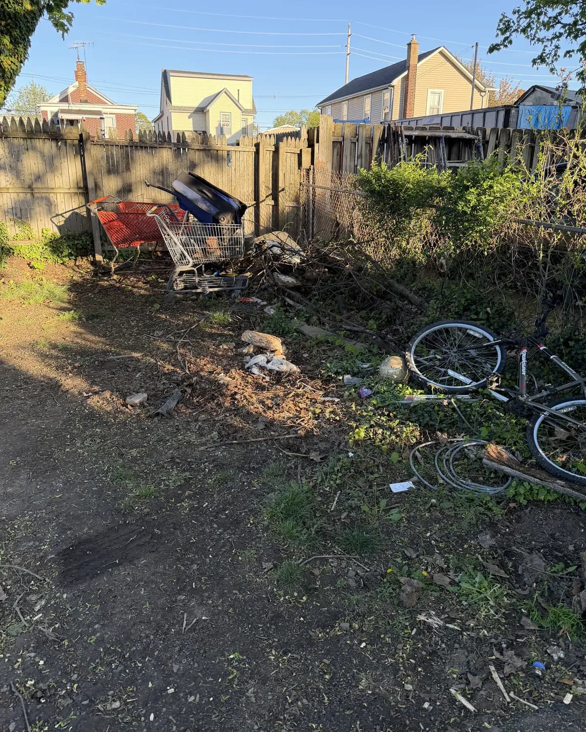 A cluttered yard full of debris and overgrowth before cleanup