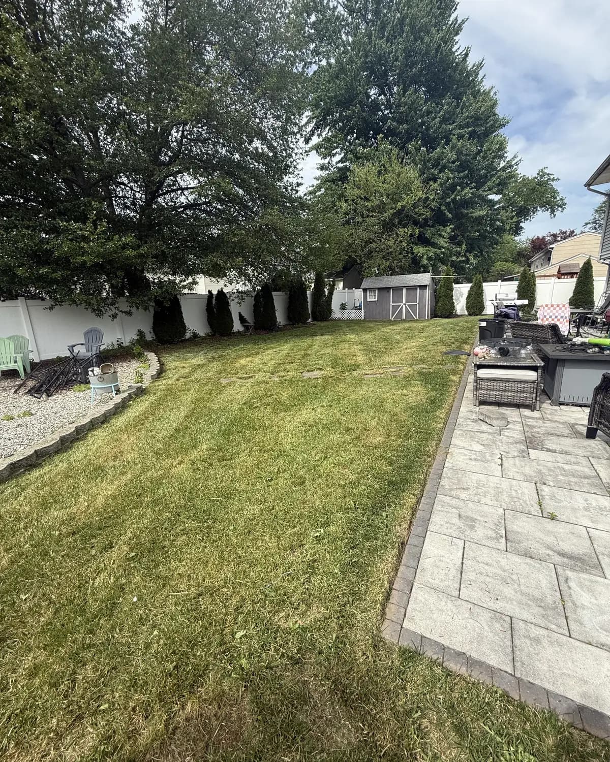 A backyard lawn cut short beside a paver patio