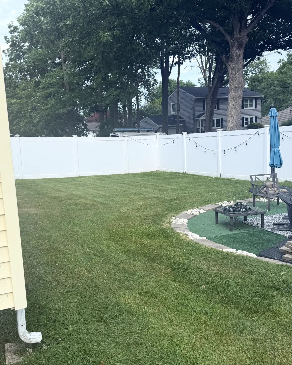 A fenced backyard lawn cut evenly around a fire pit area