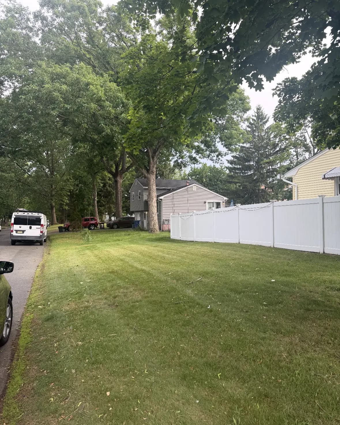 A long side lawn mowed along a white fence line