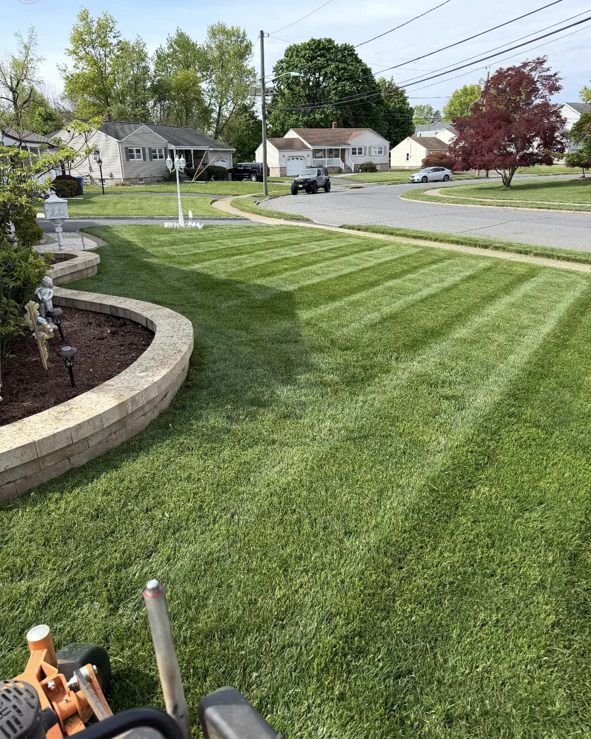 Striped lawn curving around a stone retaining wall